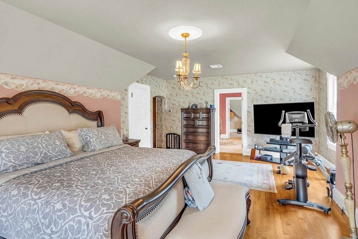 Seating area within the primary bedroom features an exercise setup and a wooden dresser.