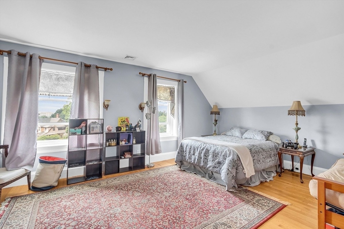 Guest bedroom displays a simple design with light blue walls and a large area rug.