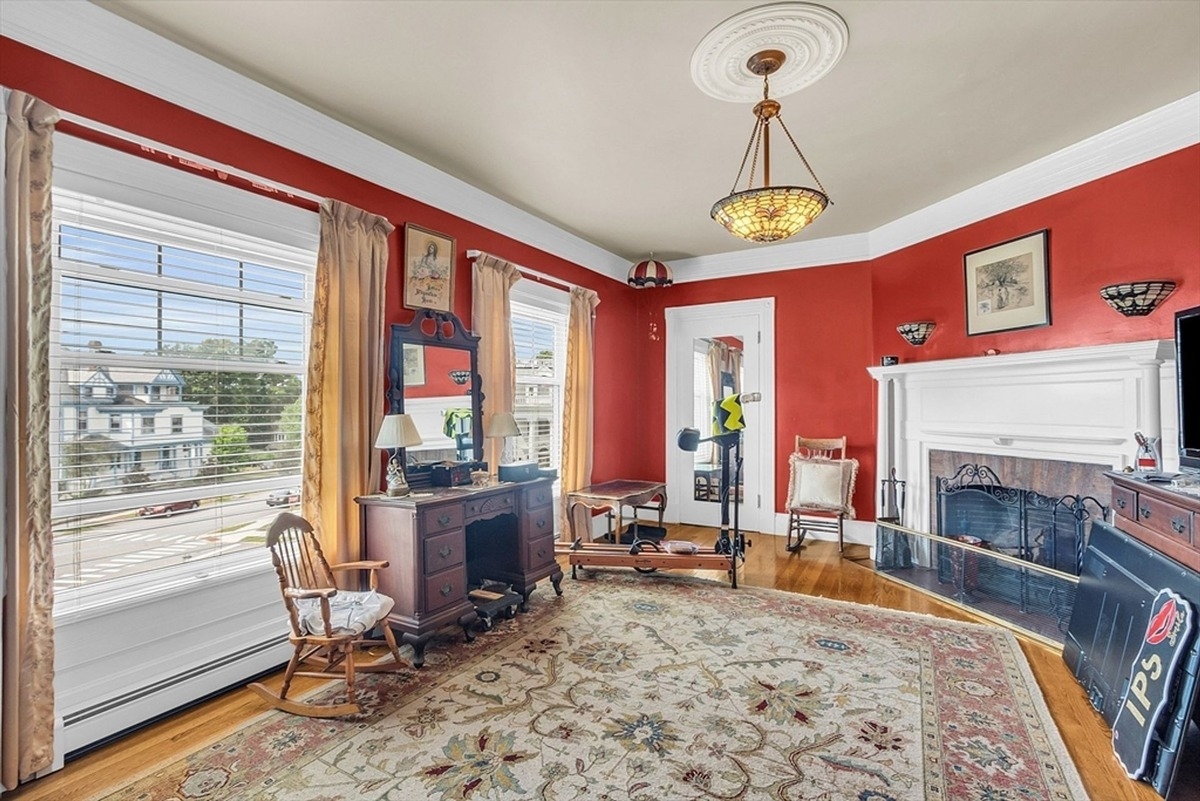 Sitting room offers a fireplace, a red accent wall, and views of the outdoors.