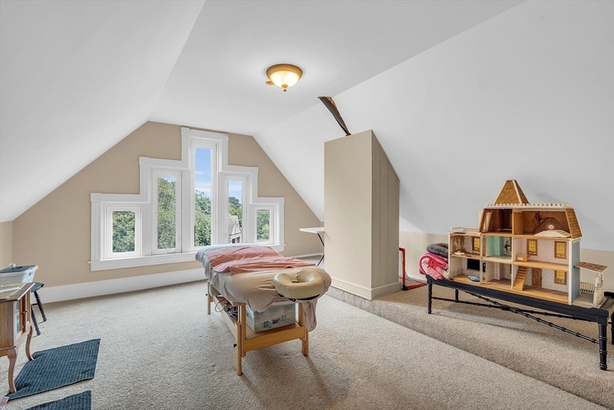 Attic room features slanted ceilings, custom windows, and a massage table setup.