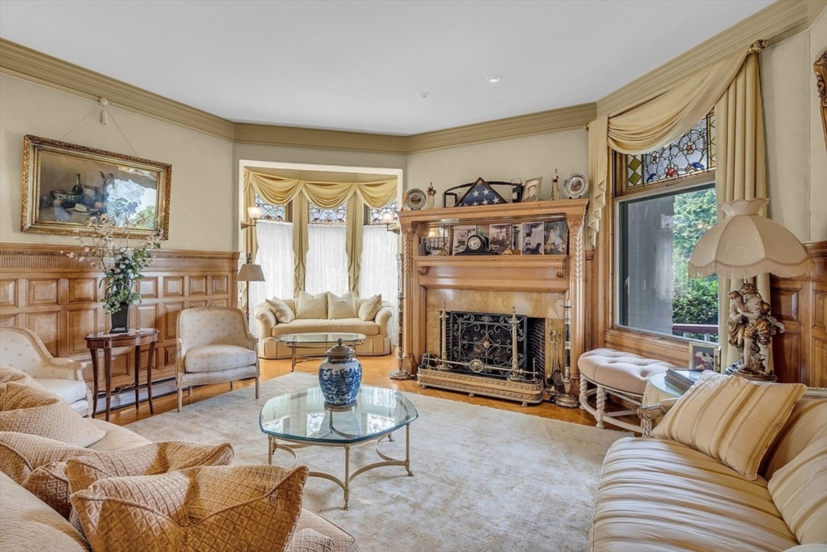 Living room with paneled walls, a marble fireplace, and stained glass windows.