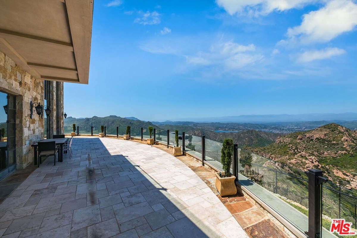 Expansive outdoor patio lined with glass railings, offering sweeping mountain and city views.