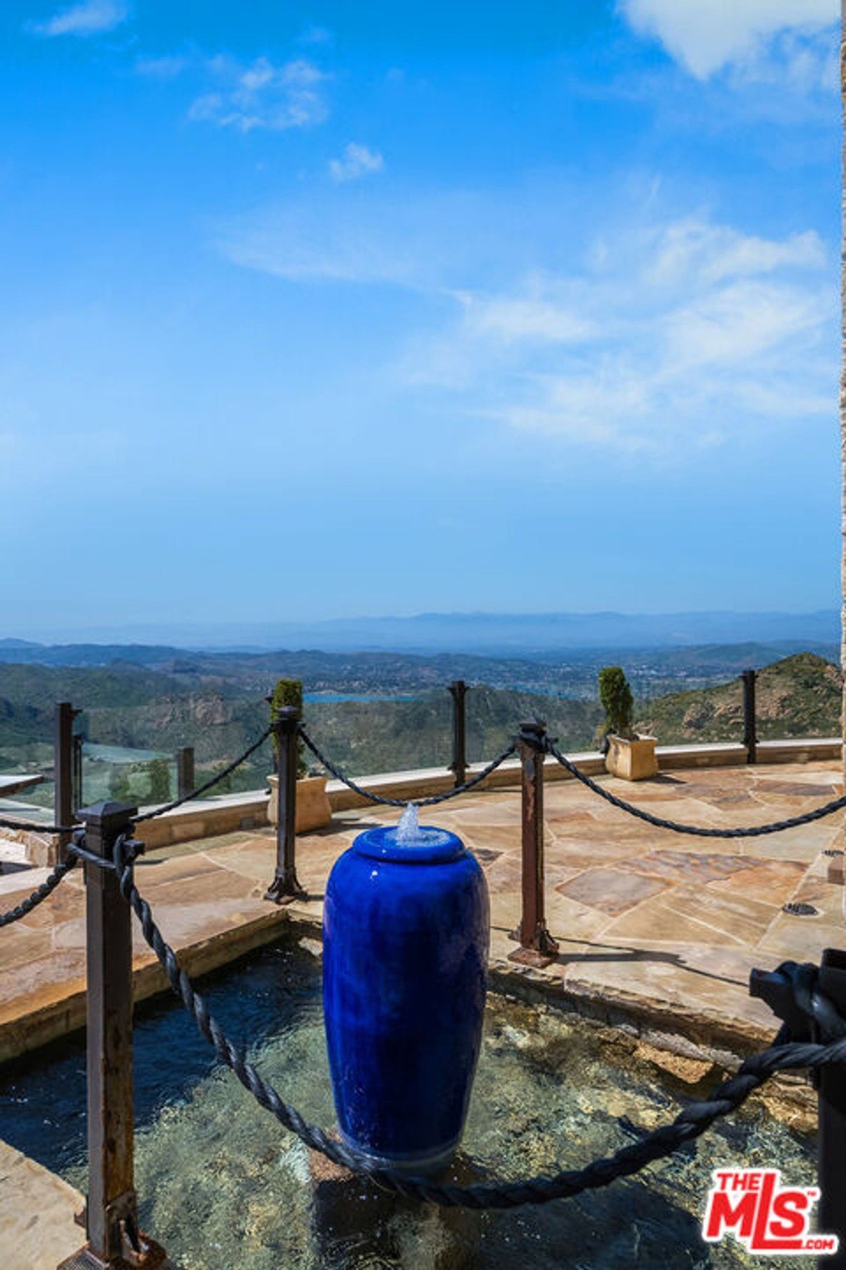 Blue ceramic water feature on a stone platform surrounded by decorative rope barriers and a scenic viewpoint.