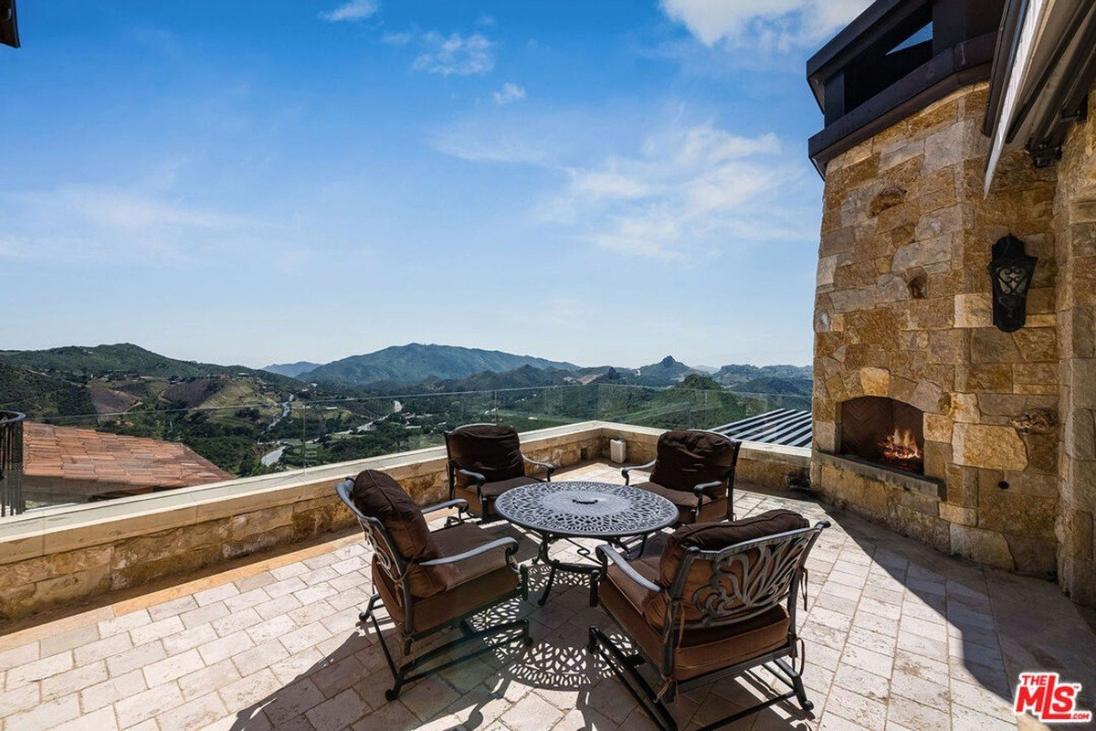 Private terrace with a stone fireplace and metal furniture, creating a serene spot to enjoy mountain vistas.