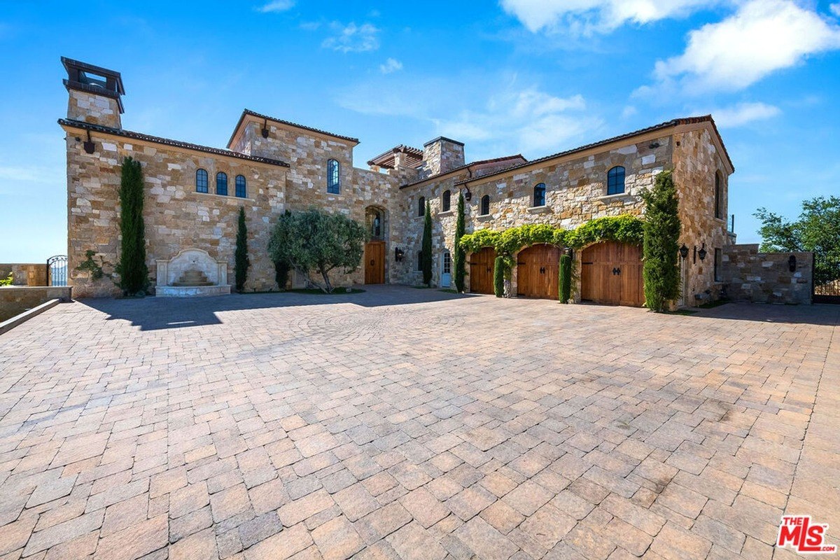 Expansive courtyard with ivy-covered garage doors and arched stone architecture.