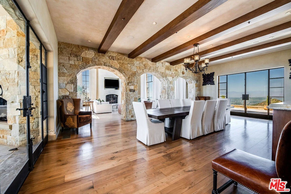 Dining area with arched stone accents, a rustic chandelier, and large windows offering panoramic views.