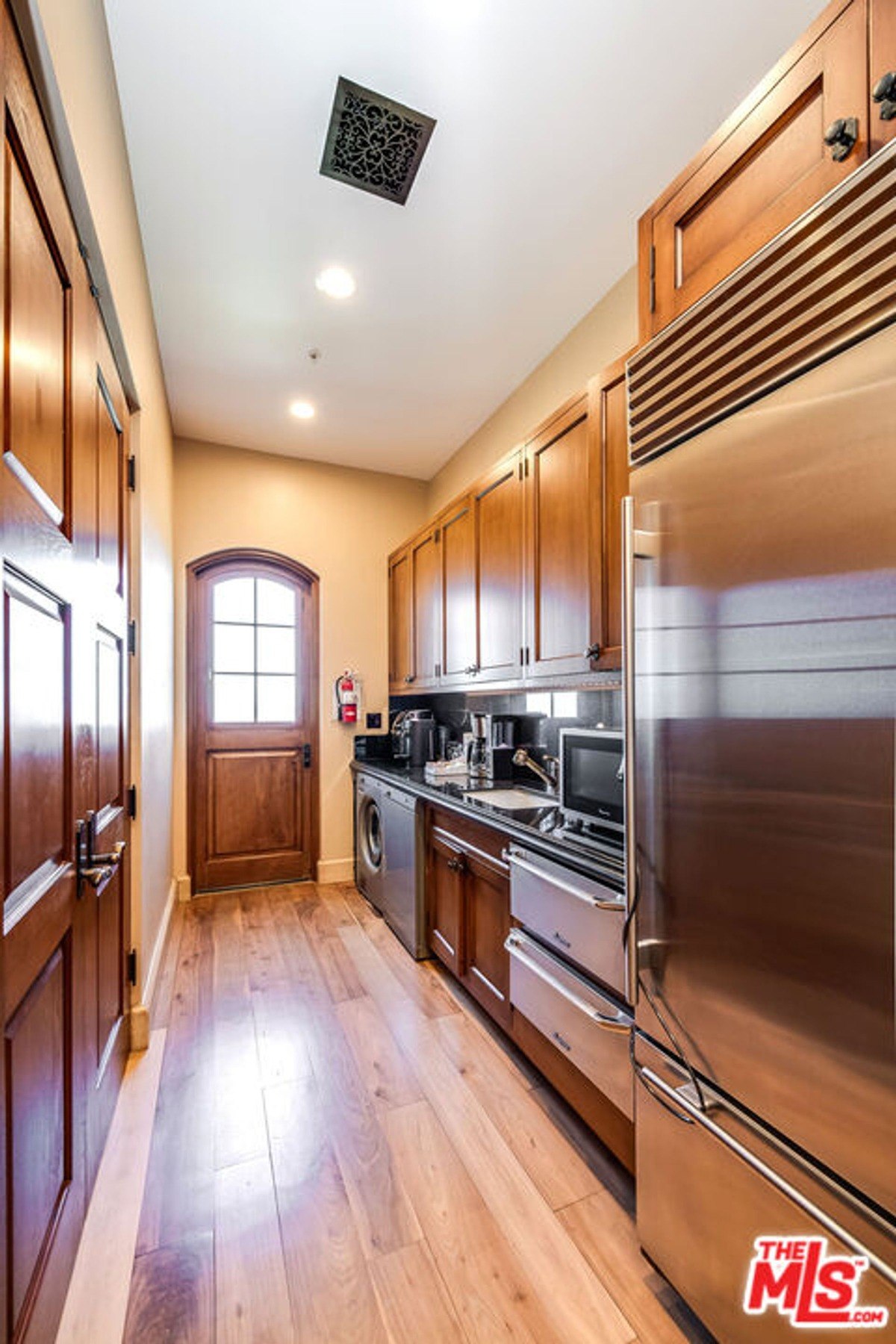 Compact butler’s pantry equipped with stainless steel appliances and additional cabinetry.