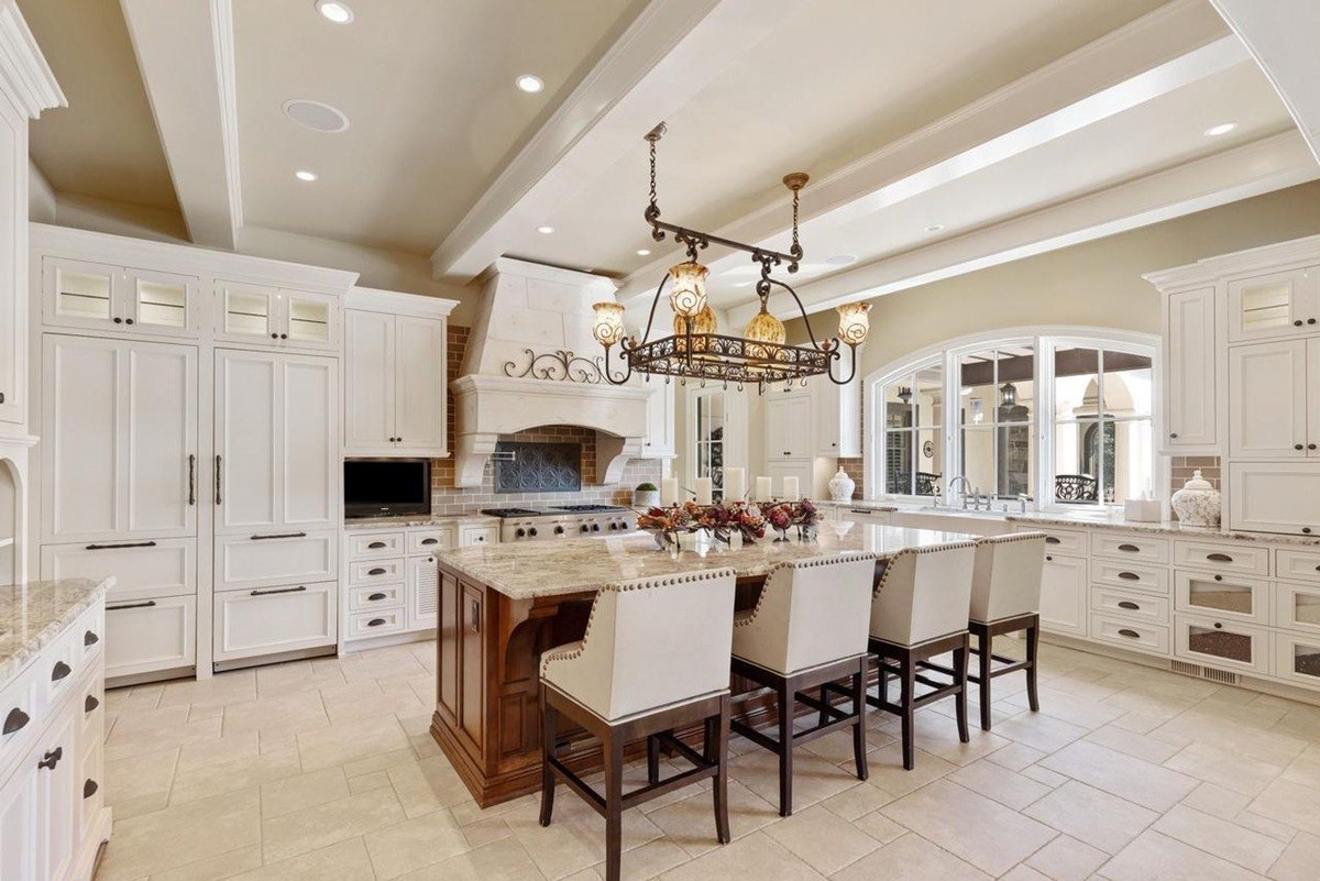 Kitchen with white cabinetry, a large island, and a chandelier creates an elegant and functional space for cooking and entertaining.