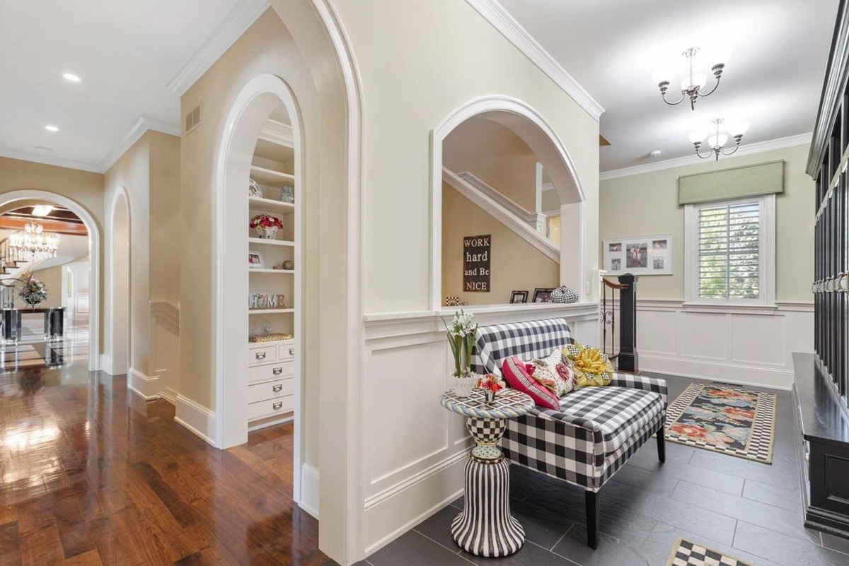 Hallway with arched doorways, built-in shelving, and a cozy seating nook creates an inviting and elegant entryway.