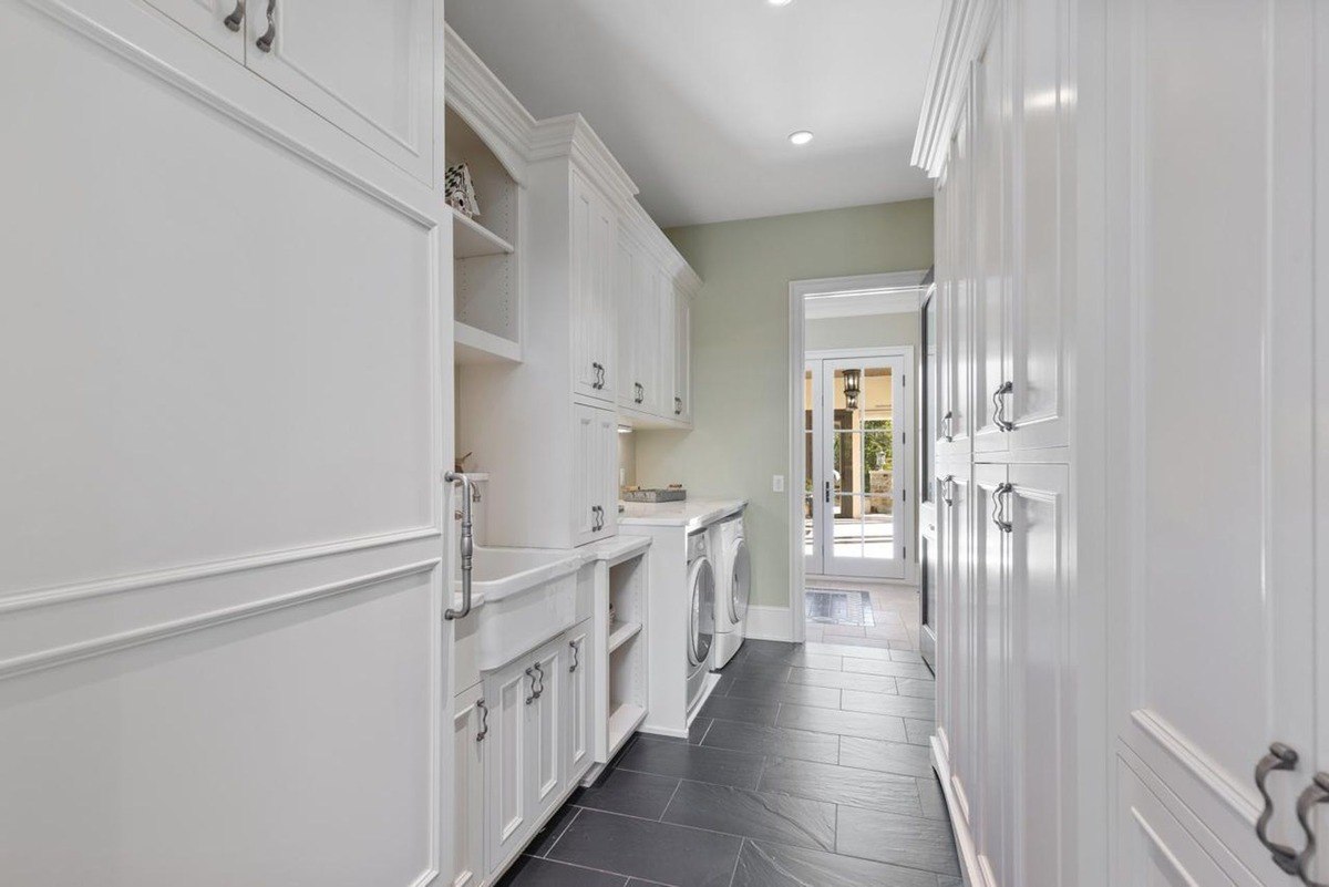 Laundry room with white cabinetry, a utility sink, and a washer and dryer offers a functional and stylish space for household chores.