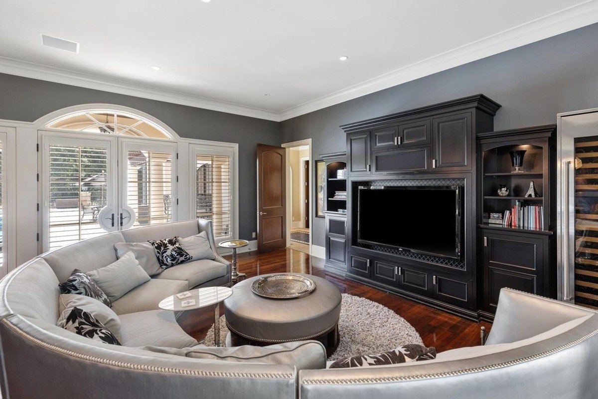 Sophisticated living room with a curved sectional sofa, a built-in entertainment center, and a wine cooler offers a luxurious space for relaxation and entertainment.