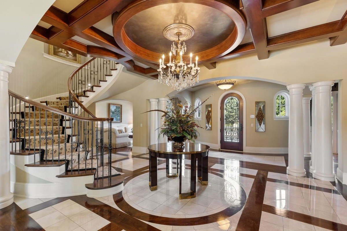 Crystal chandelier add a touch of luxury to this spacious foyer, featuring a grand staircase and a circular marble floor.