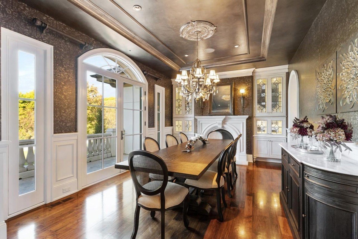 Formal dining room with a long wooden table, elegant chairs, and a dramatic chandelier creates a sophisticated setting for entertaining.