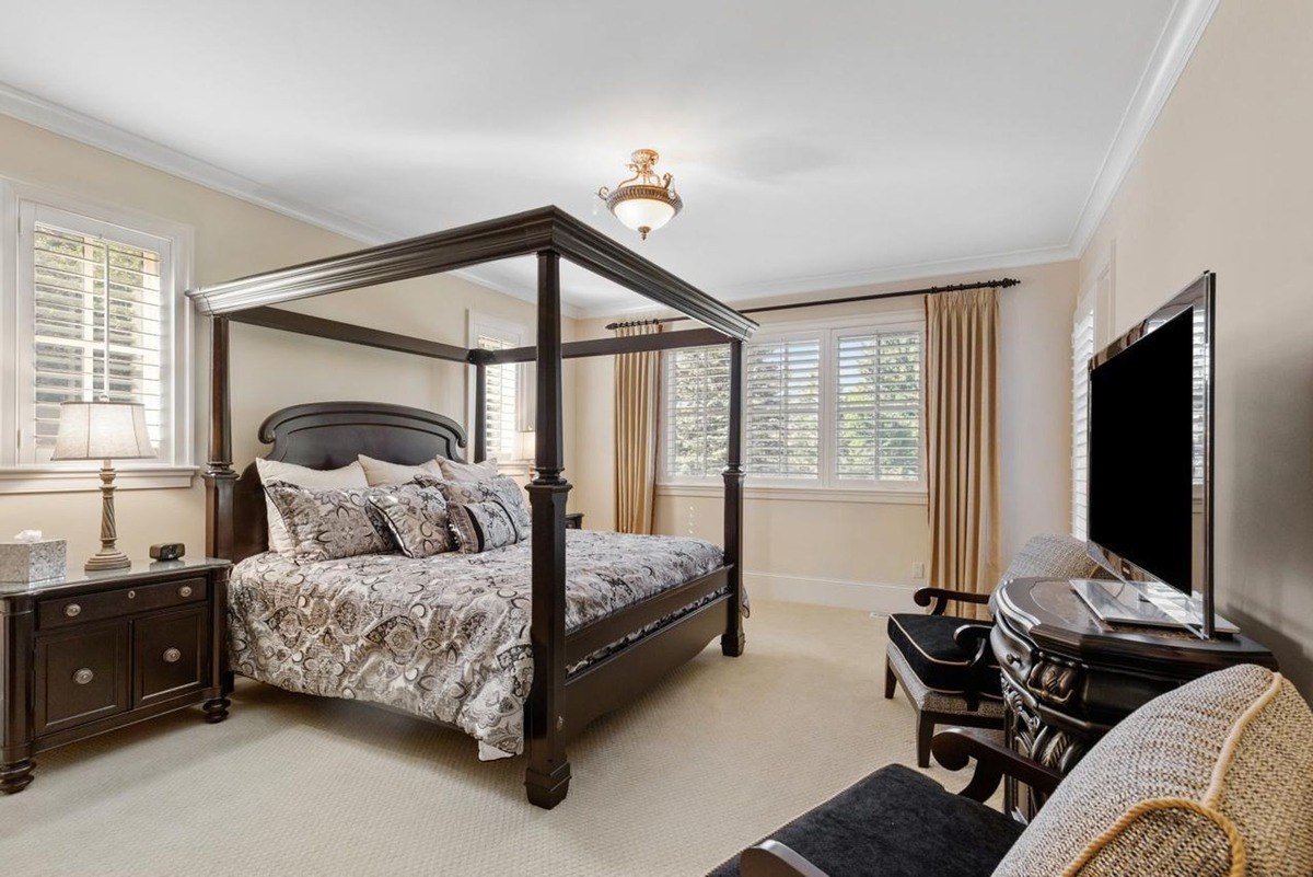 Bedroom with a four-poster bed, a flat-screen TV, and ample natural light creates a comfortable and inviting retreat.