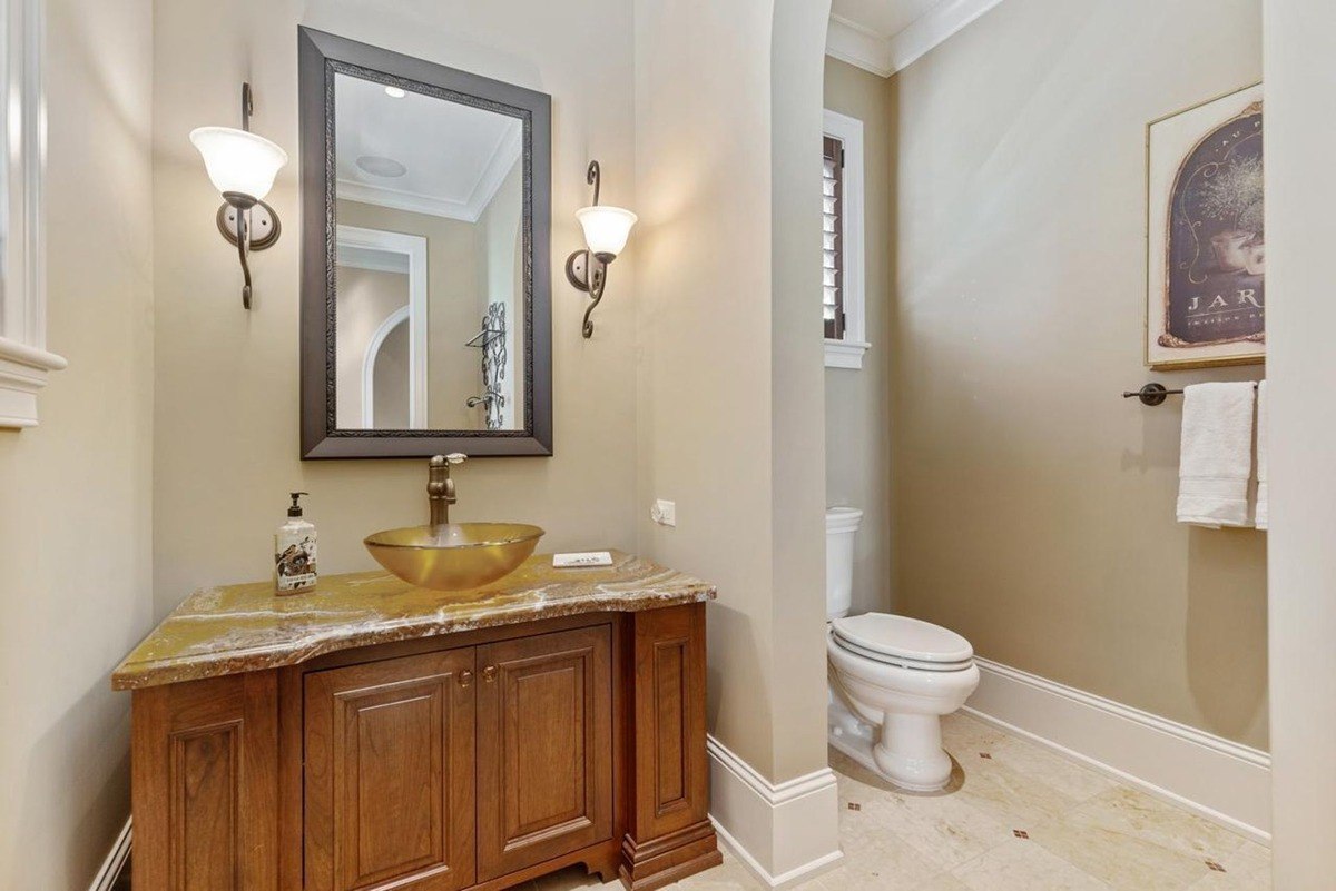 Powder room with a gold vessel sink, a framed artwork, and a decorative mirror offers a touch of elegance.