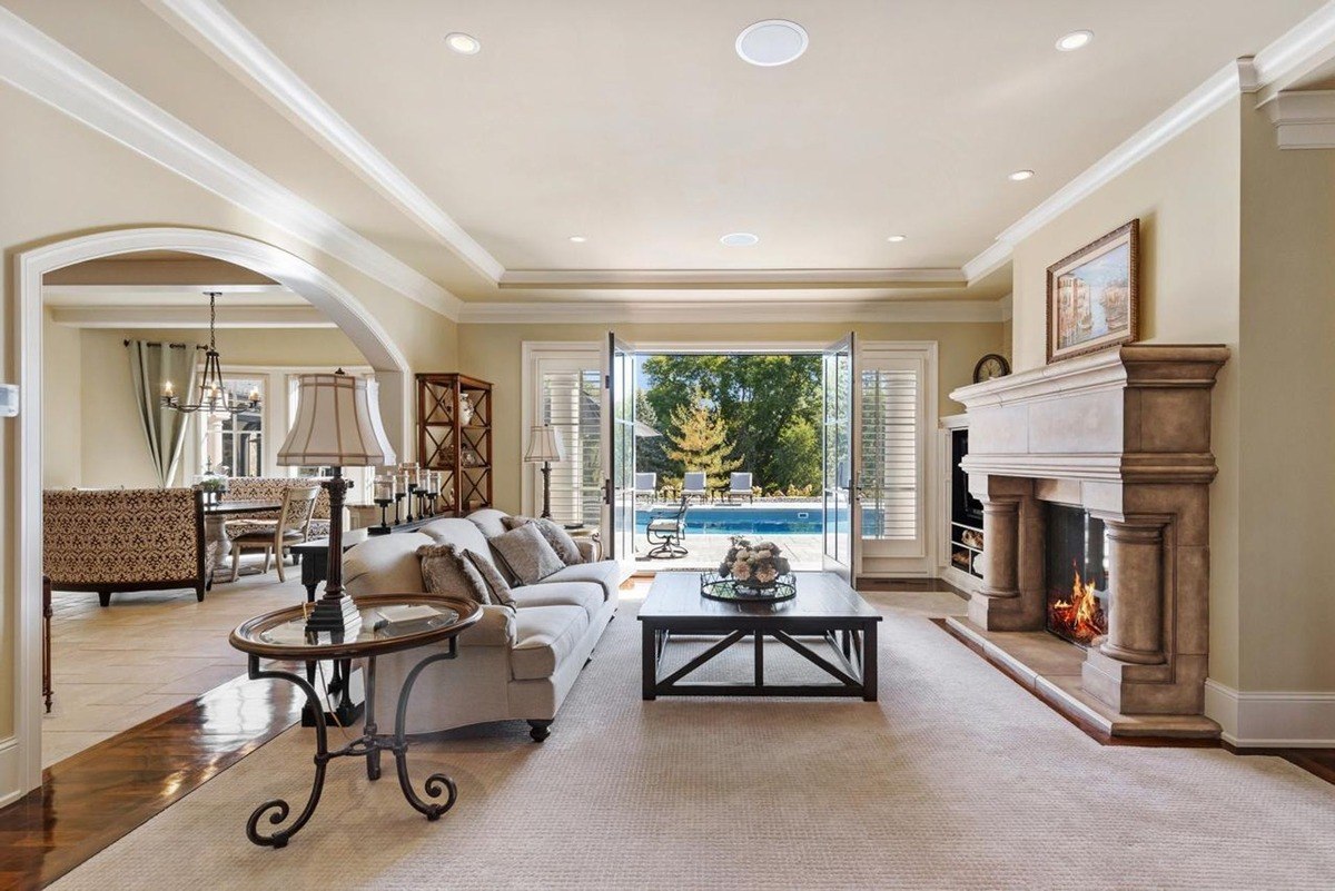 Cozy living room with a fireplace, plush seating, and French doors leading to a poolside patio offers a relaxing and inviting space.