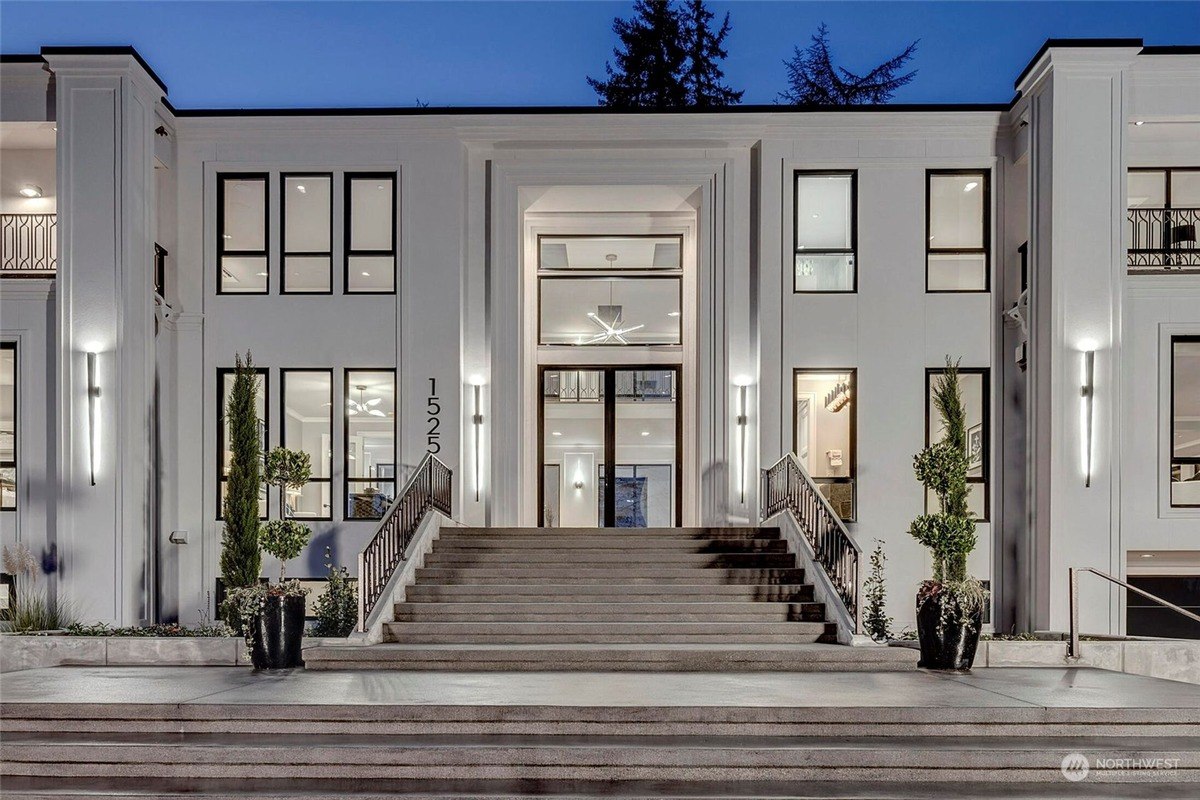 Close-up of the central entrance framed by tall pillars, large windows, and decorative potted greenery. 