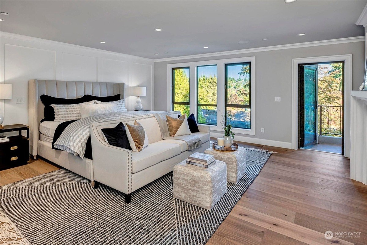 Master bedroom with large bed, sitting area, and wood floors. 