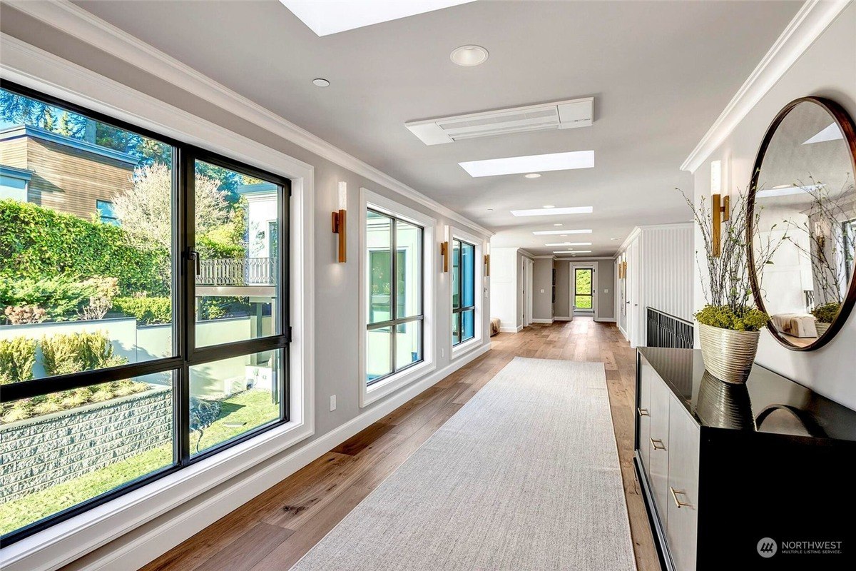 Hallway has hardwood floors, skylights, and large windows looking 