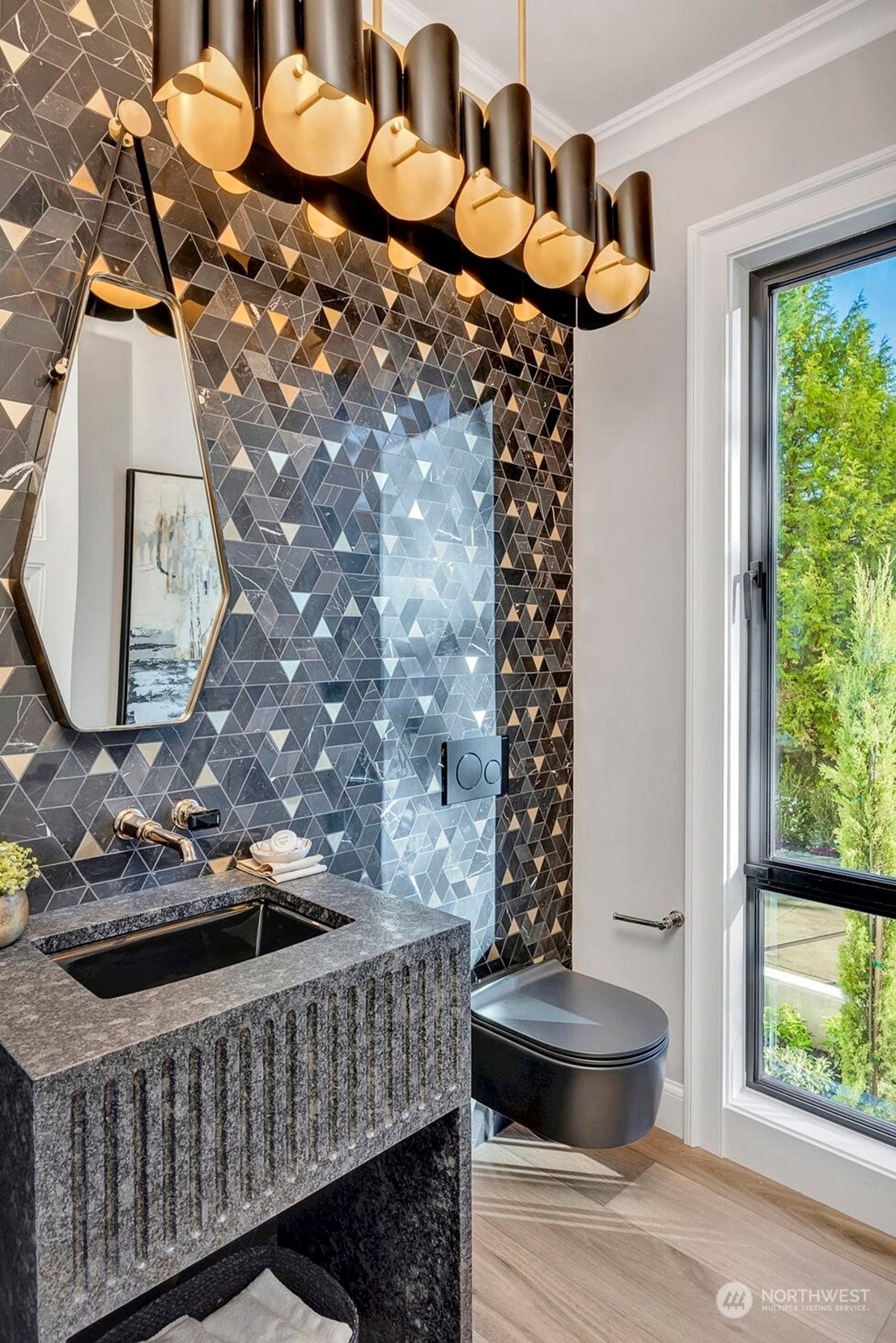 Powder room dark geometric tile, modern sink and toilet, and a window.c