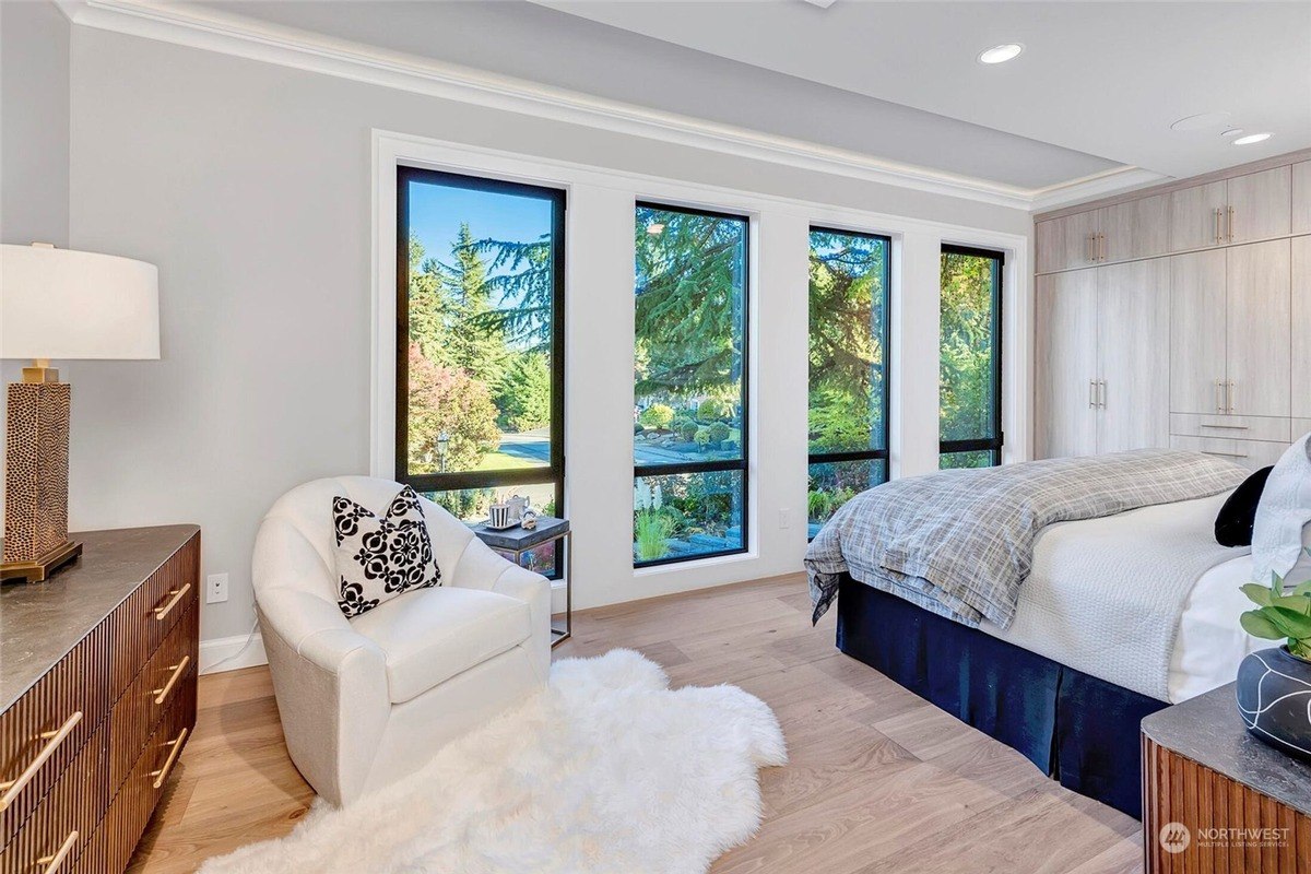 Bedroom with wood floors, large windows, and a bed with a navy blue bedskirt.