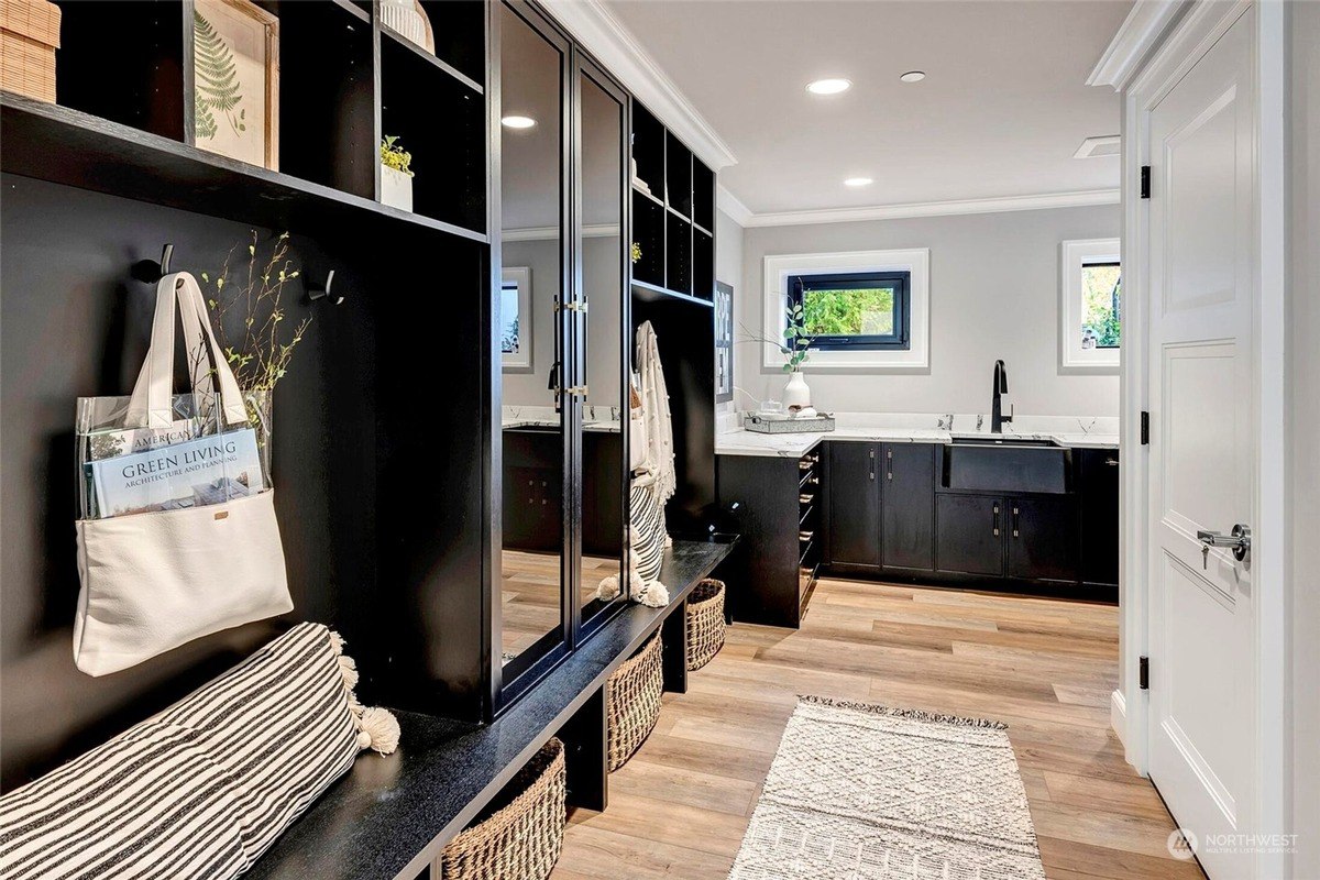 Mudroom has black built-in cabinets with storage, a bench, and a farmhouse sink.