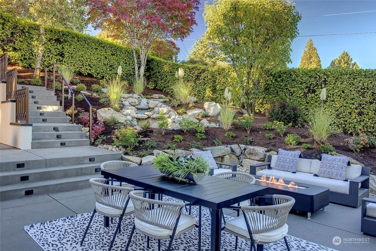 Outdoor kitchen has built-in appliances, a black granite countertop, and a patterned rug.