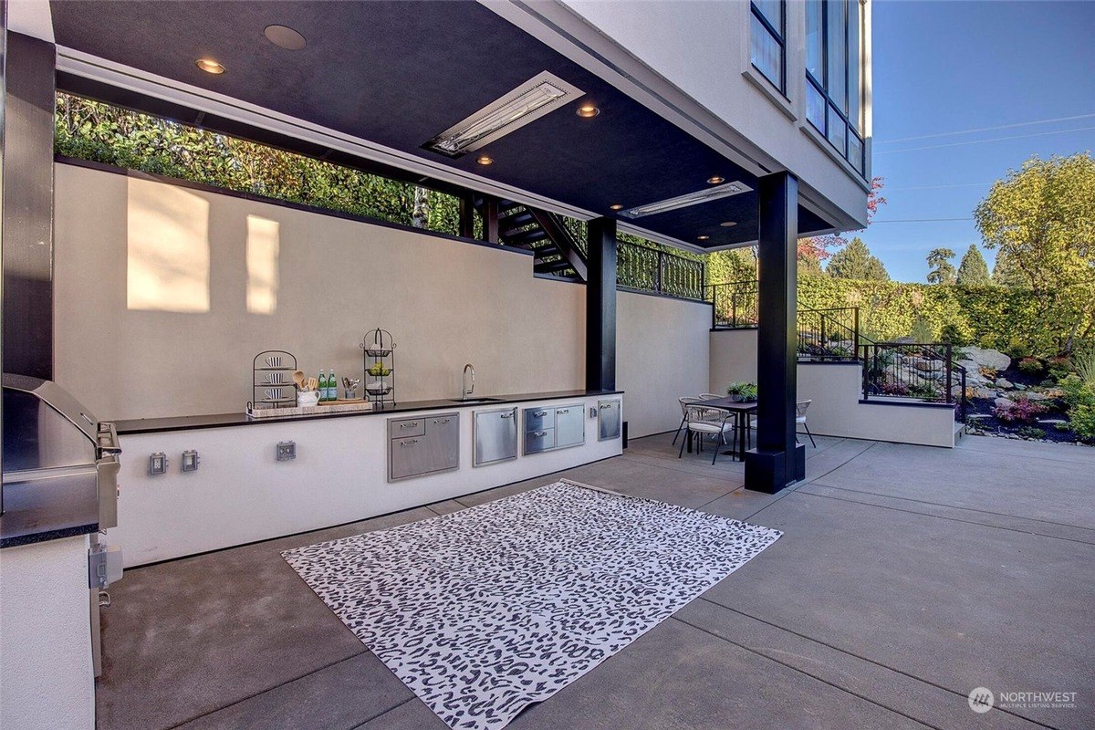 Home has a modern design, outdoor patio with fire pit, and a landscaped backyard at night.