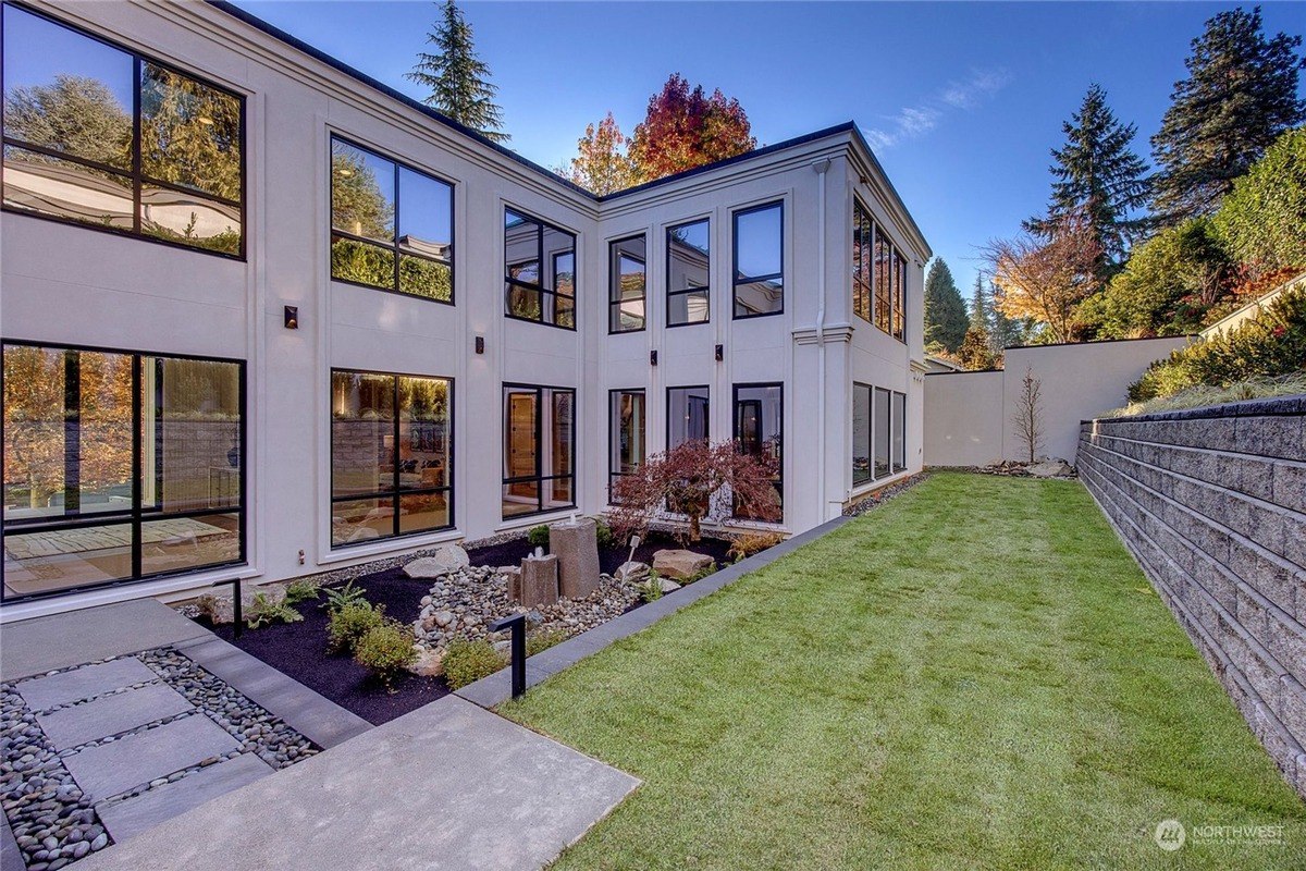 Modern home has large windows, a landscaped courtyard, and a retaining wall.