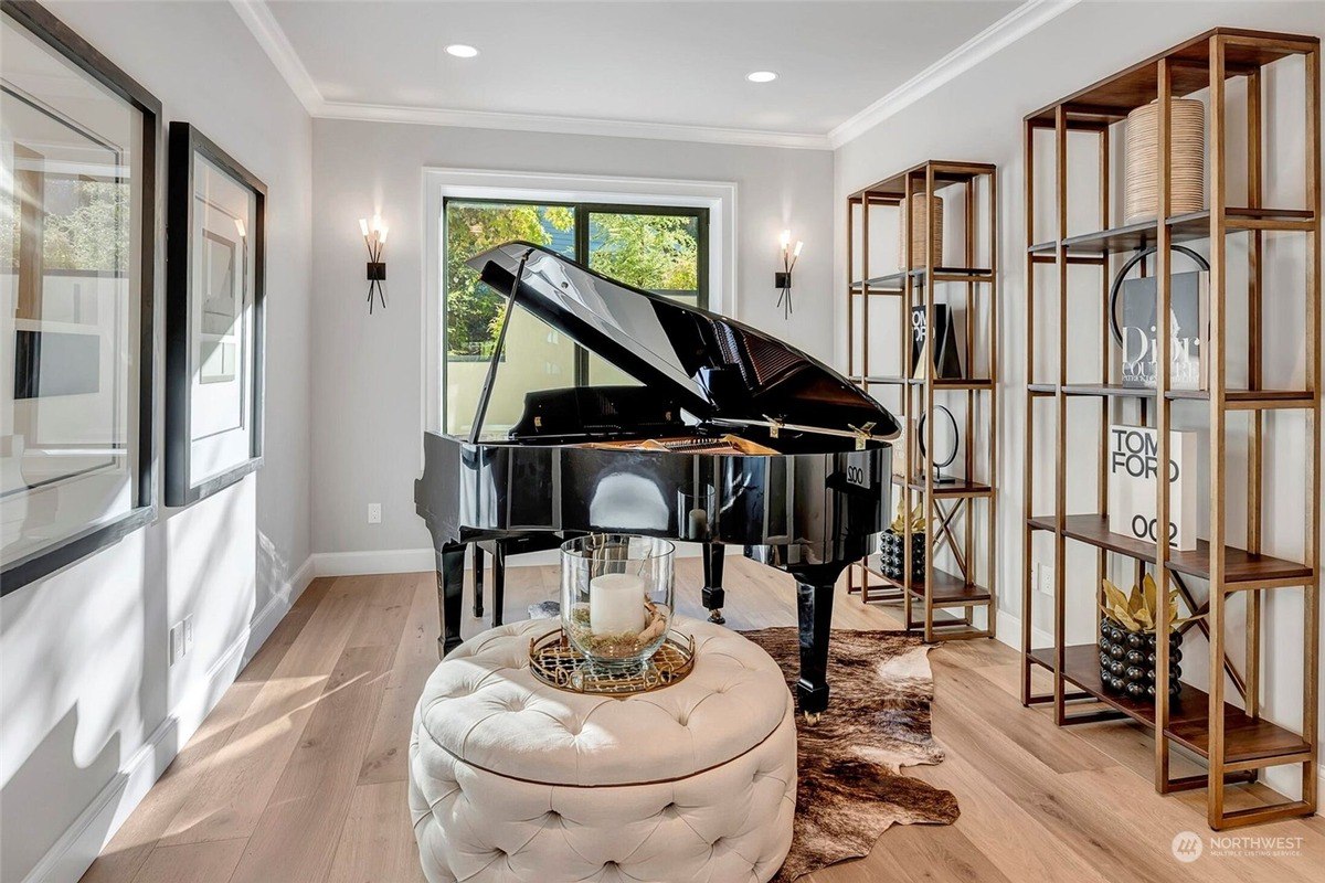 Music room featuring a grand piano, tufted ottoman, and modern shelving with decorative accents. 