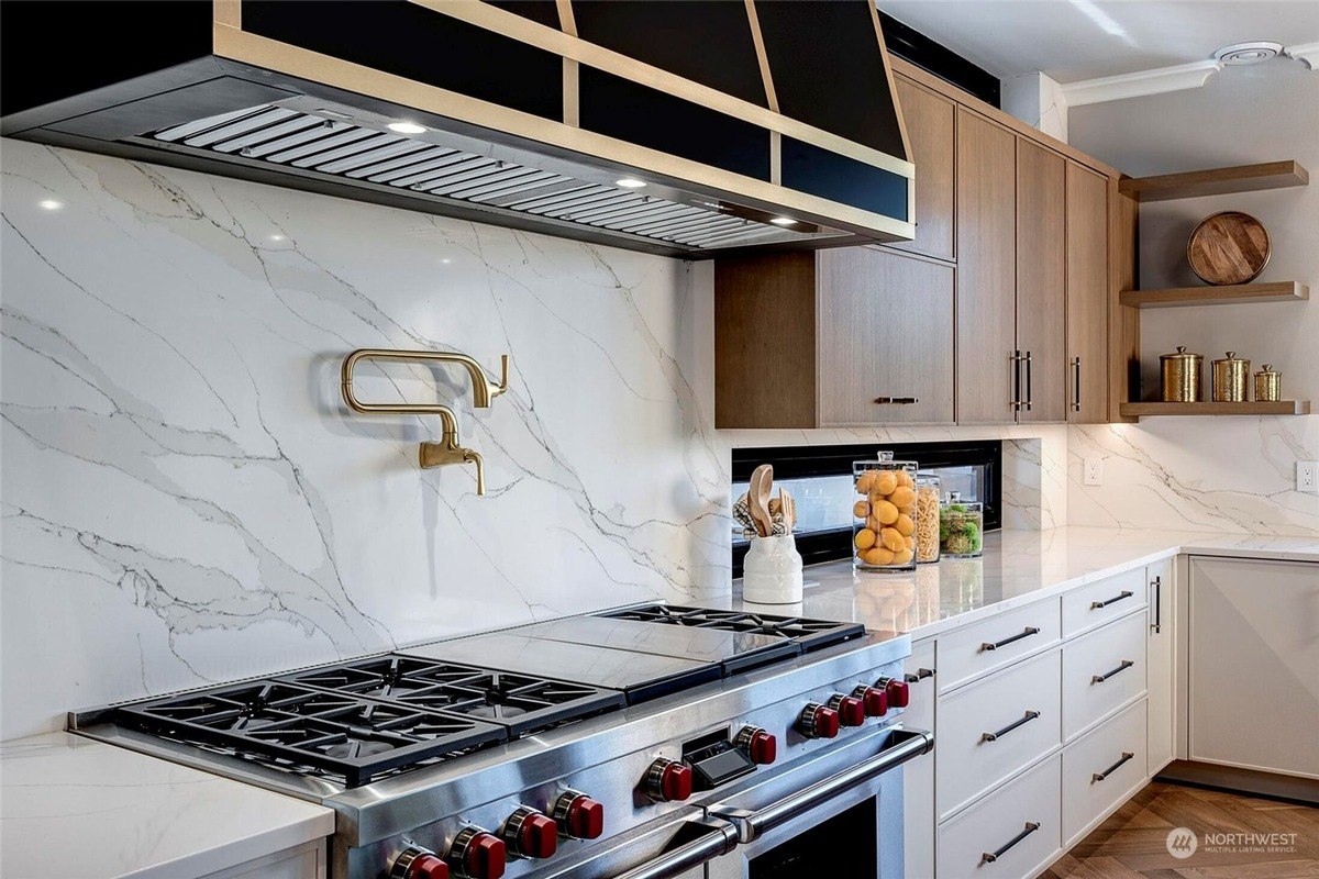 Kitchen features a marble backsplash, gold-tone pot filler, and a professional-grade stove with six burners. 