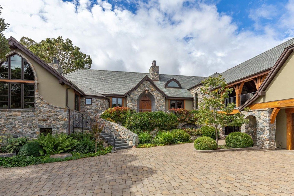 Stone-clad exterior with arched entrance and lush greenery.