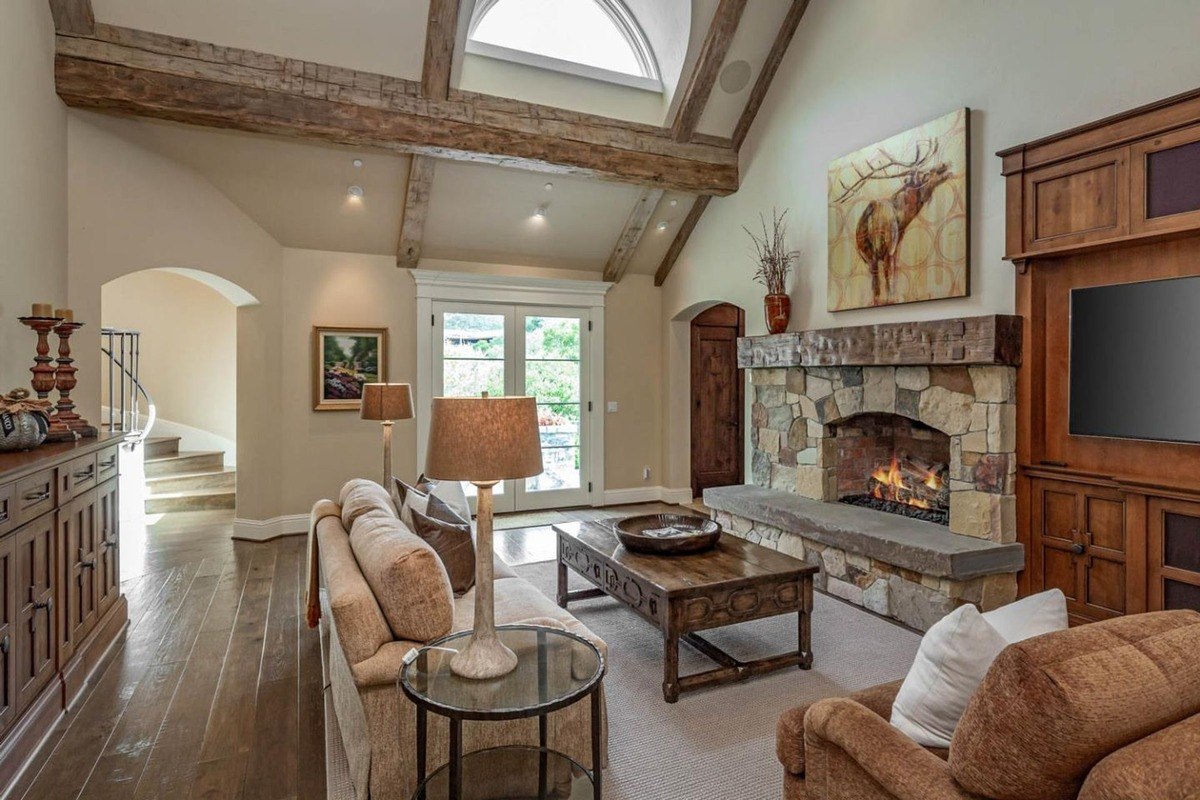 Family room with a vaulted ceiling, stone fireplace, and cozy seating.