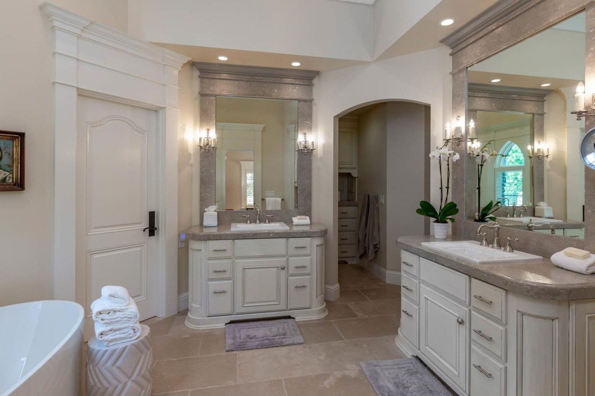 Dual-sink bathroom with stone countertops, large mirrors, and elegant lighting.