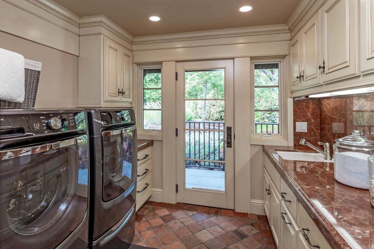 Laundry room with marble countertops, modern appliances, and an exterior door.