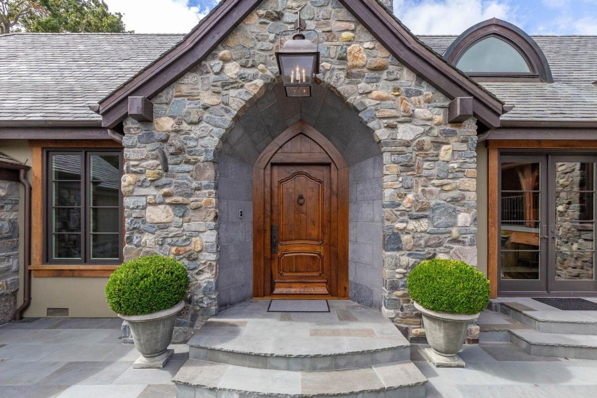 Close-up of the wooden front door framed by stonework and planters.