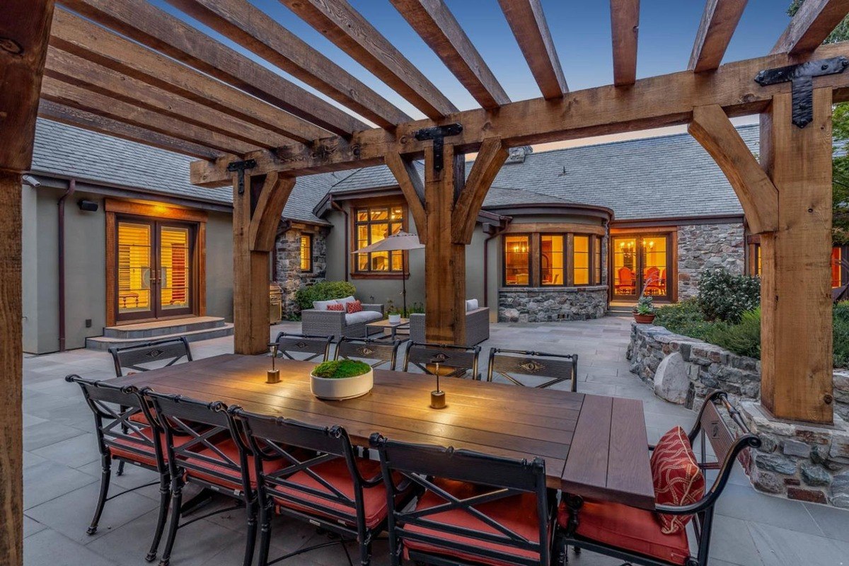 Dining pergola a dining table with chairs sits under a rustic wood pergola.