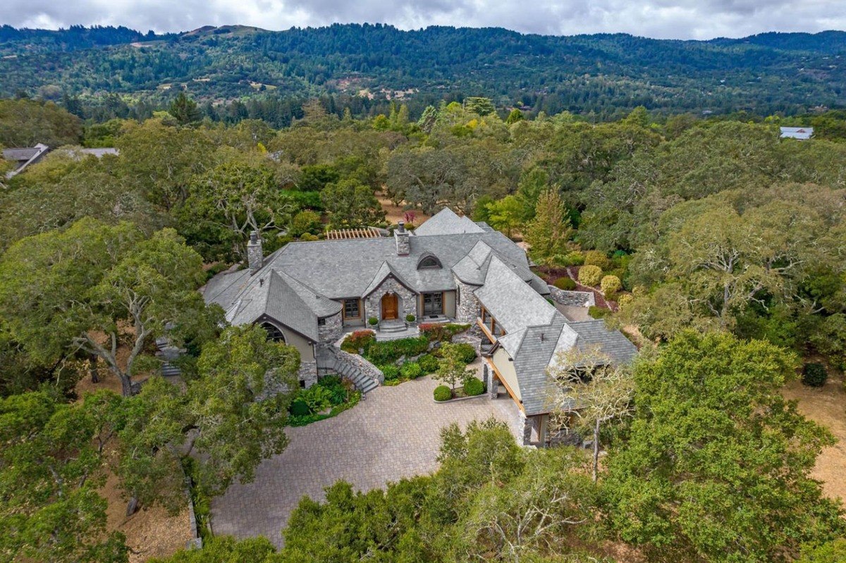 Aerial view of home, the home is surrounded by mature trees and lush landscaping.