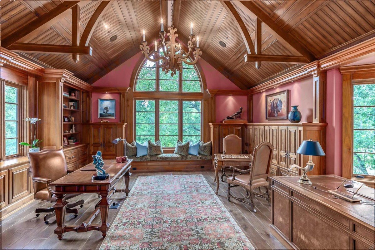 Home office with vaulted ceiling, wood paneling, and a large window seat.