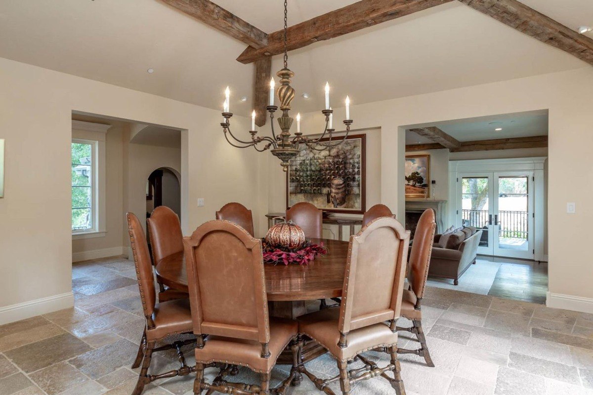 Dining room with a round wooden table, leather chairs, and a chandelier.