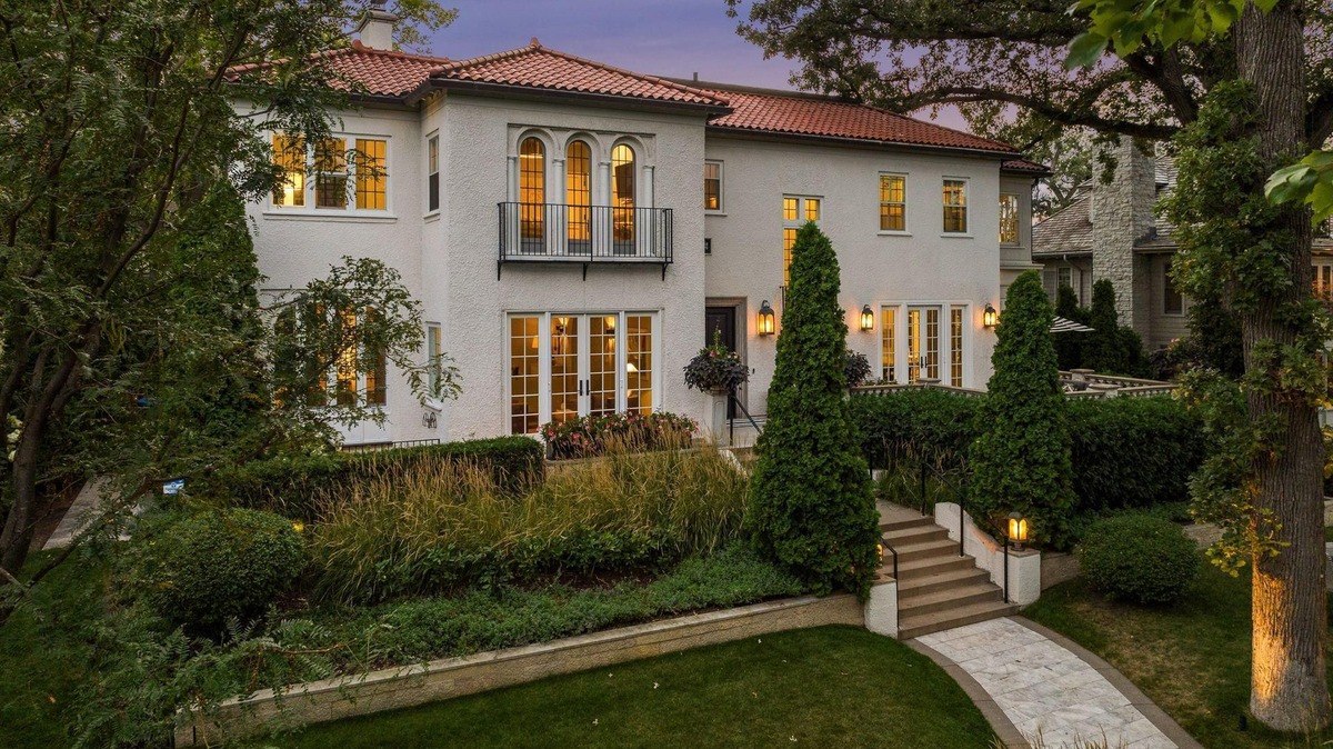 Large white house with a red tile roof, landscaping, and a stone walkway.