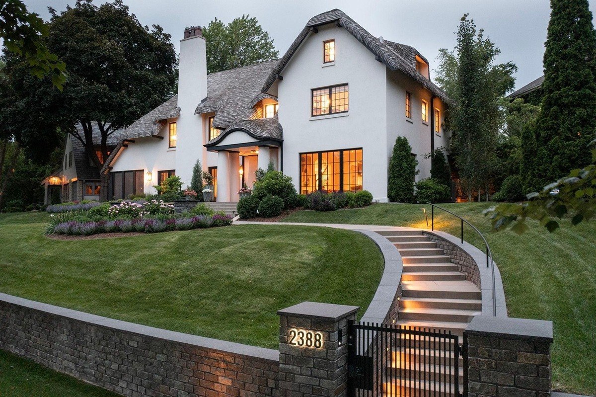 Two-story white house with a thatched roof and a stone walkway leading to the entrance.