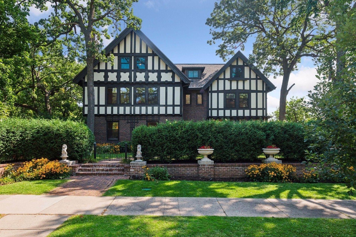 Large Tudor-style house with black and white exterior, situated on a landscaped lawn.