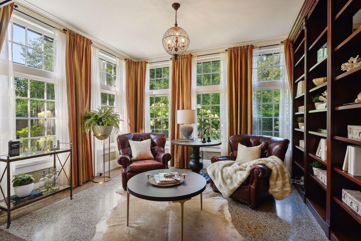 Sunroom with two leather armchairs, a coffee table, and a large bookcase.