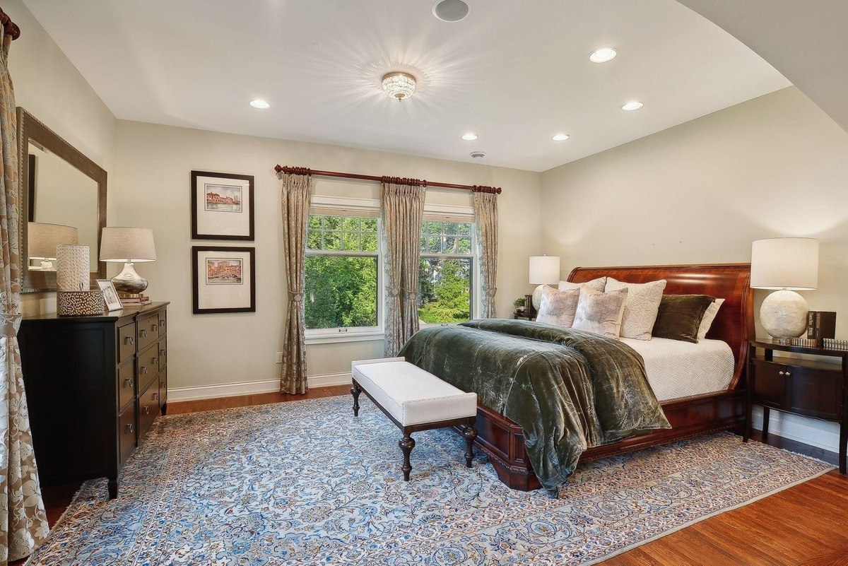 Master bedroom with a large bed, patterned rug, and hardwood floors.