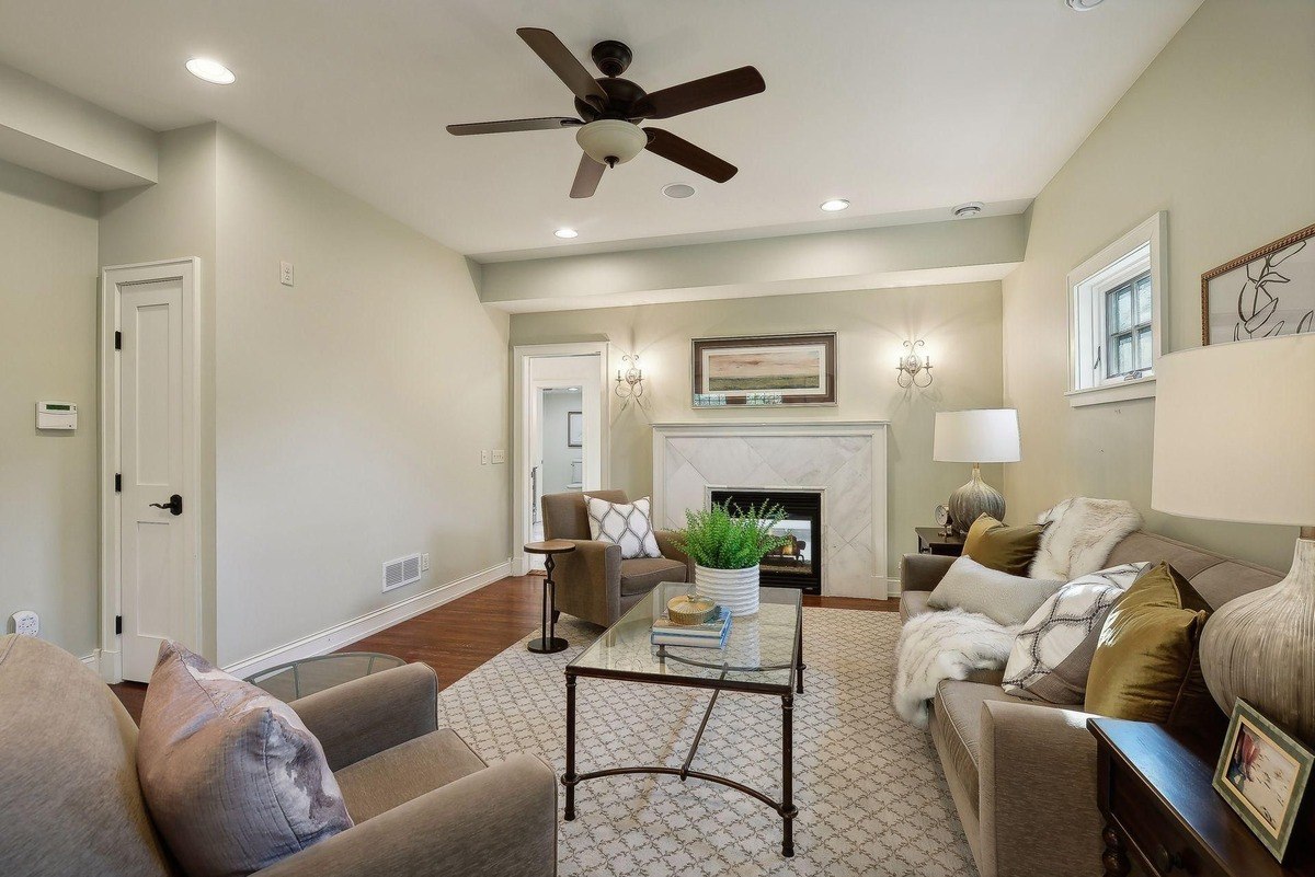 Family room with a ceiling fan, neutral-toned furniture, and a fireplace.