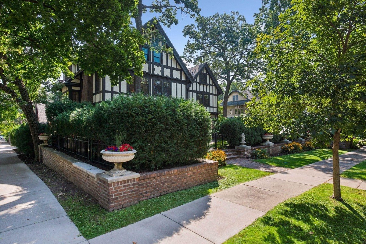 House with black and white half-timbered exterior, situated on a tree-lined street.