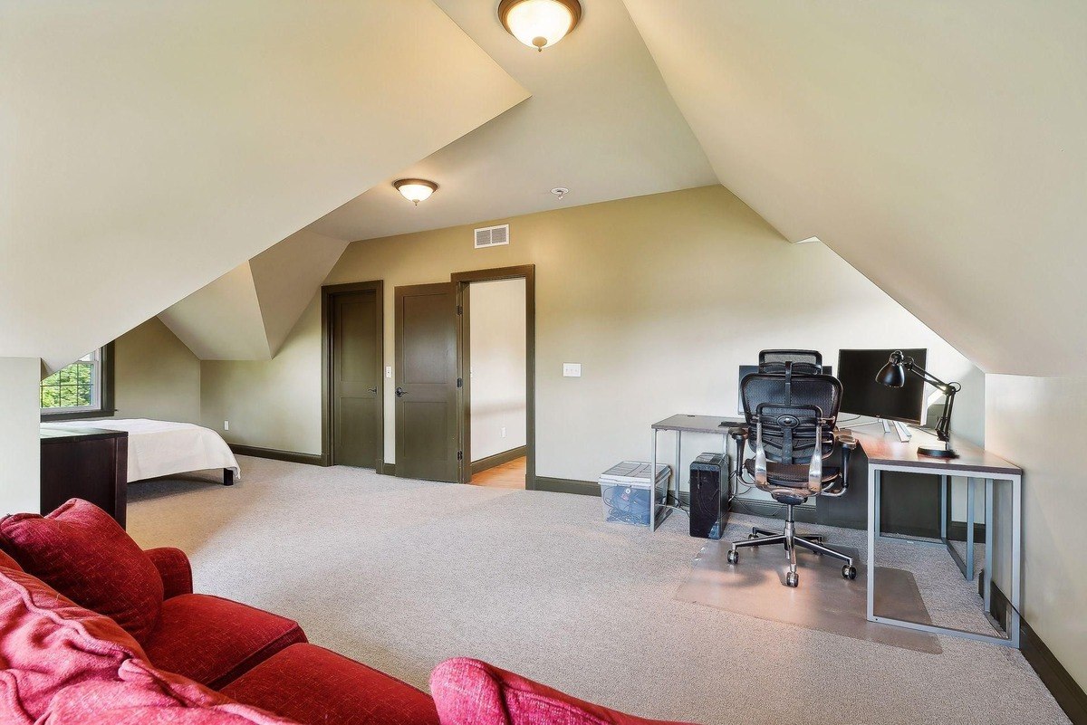 Attic room with carpeted floors, a bed, and a workspace with a computer.