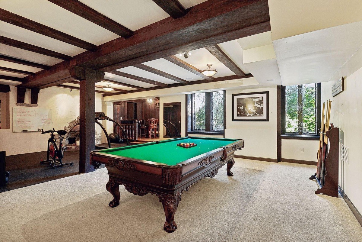 Game room with a pool table, exercise bike, and exposed wooden beams.