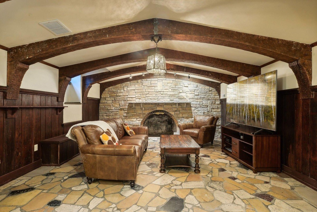 Family room features a stone fireplace, leather furniture, and a large flat-screen TV.